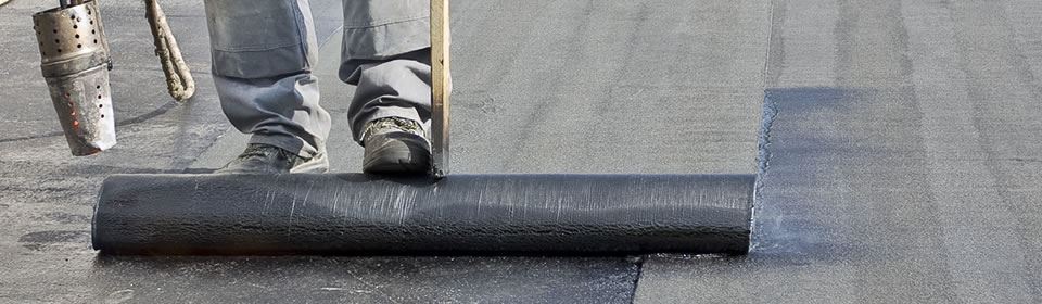 Bitumen dakbedekking uitrollen op plat dak